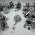 Multiple clear plastic retractable badge reel pens with silver metal clips and rings, scattered on a plain white background.