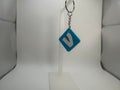 A blue diamond-shaped keychain with a white stylized letter 'V' on a silver split ring, displayed on a clear plastic stand against a white background.